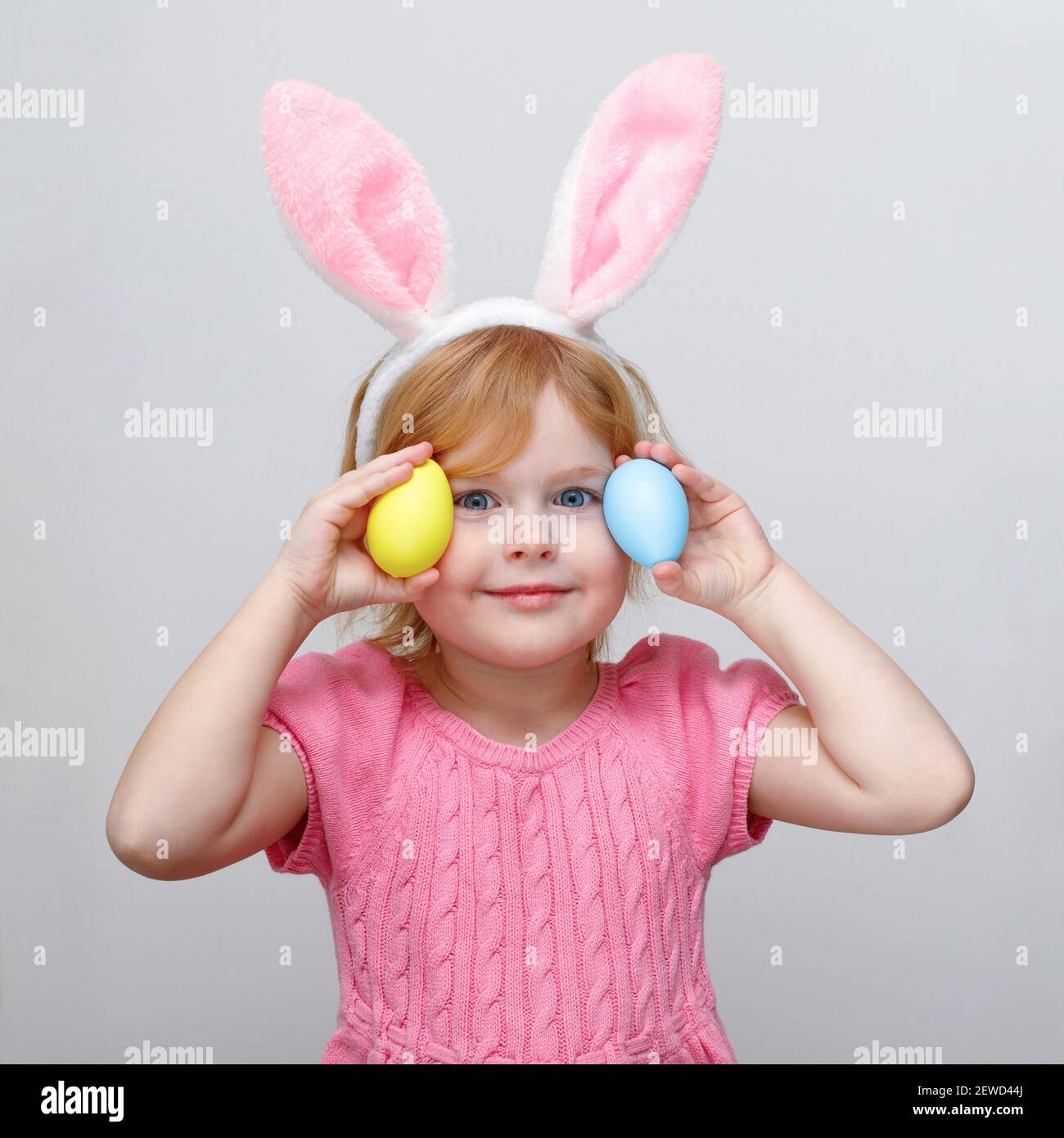 Beautiful smiling little girl wearing Easter bunny ears and holding