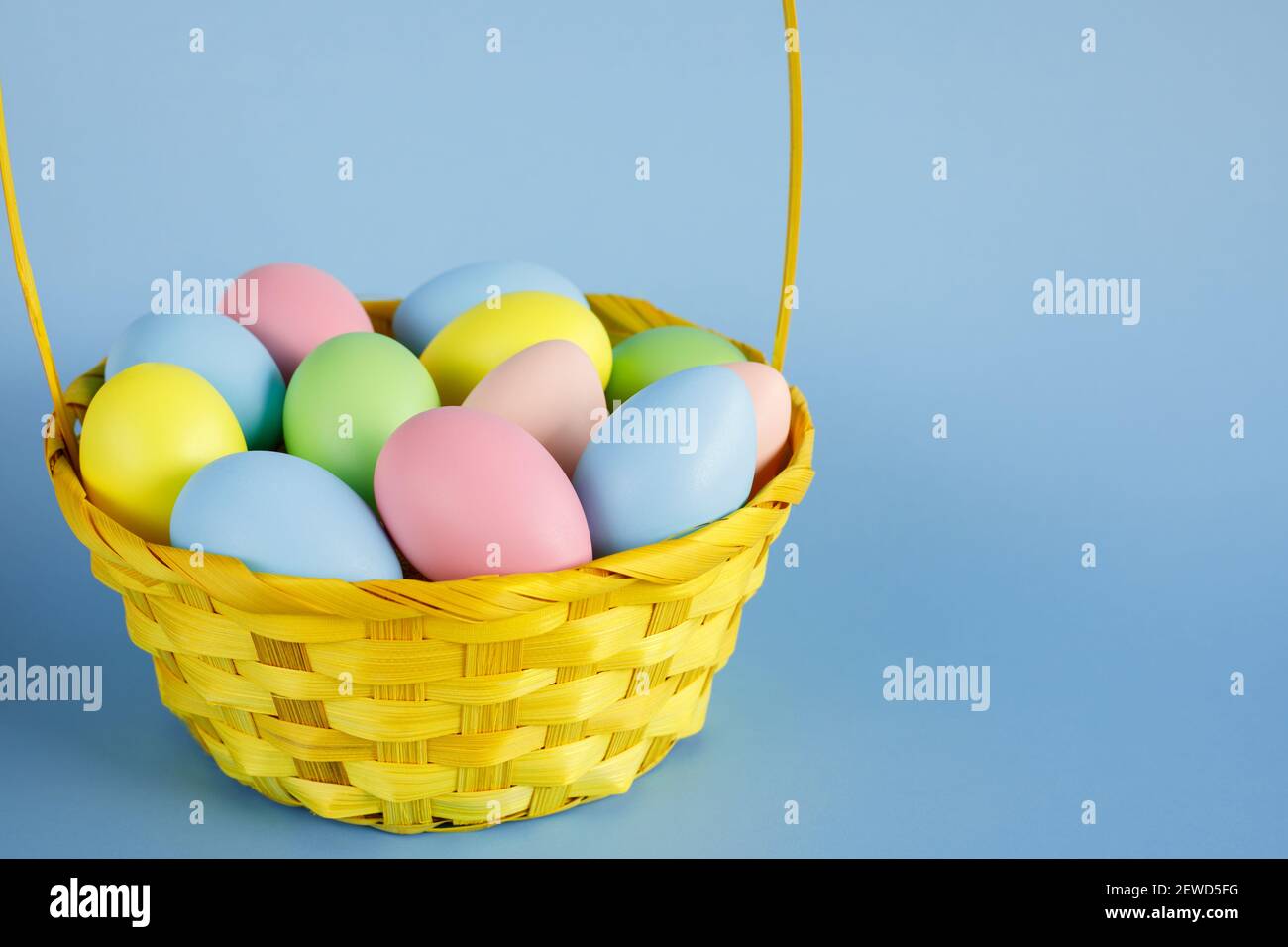 Easter eggs in basket with copy space on blue background. Easter composition. Stock Photo