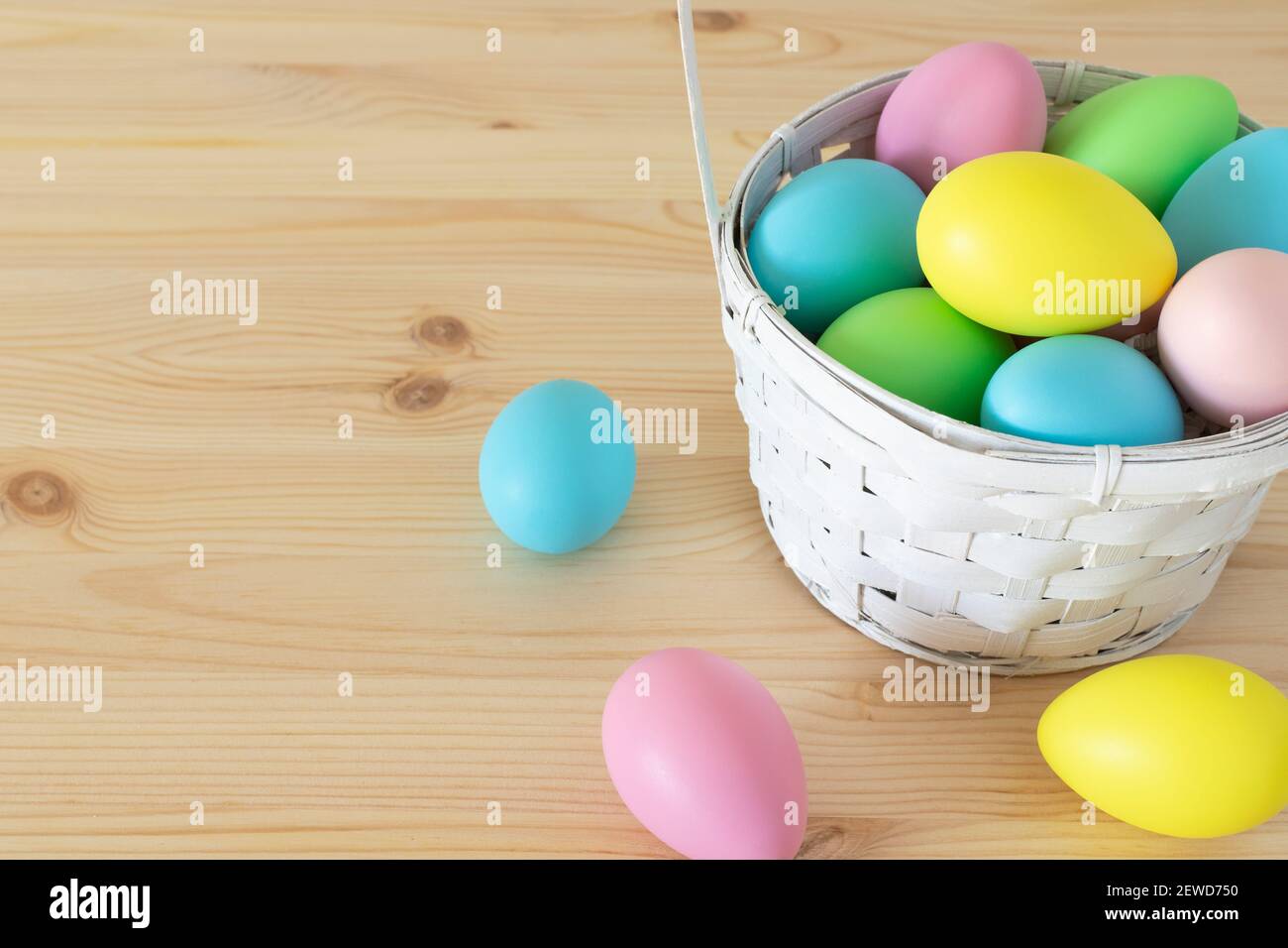 Easter colored eggs in the basket on wooden table background Stock Photo