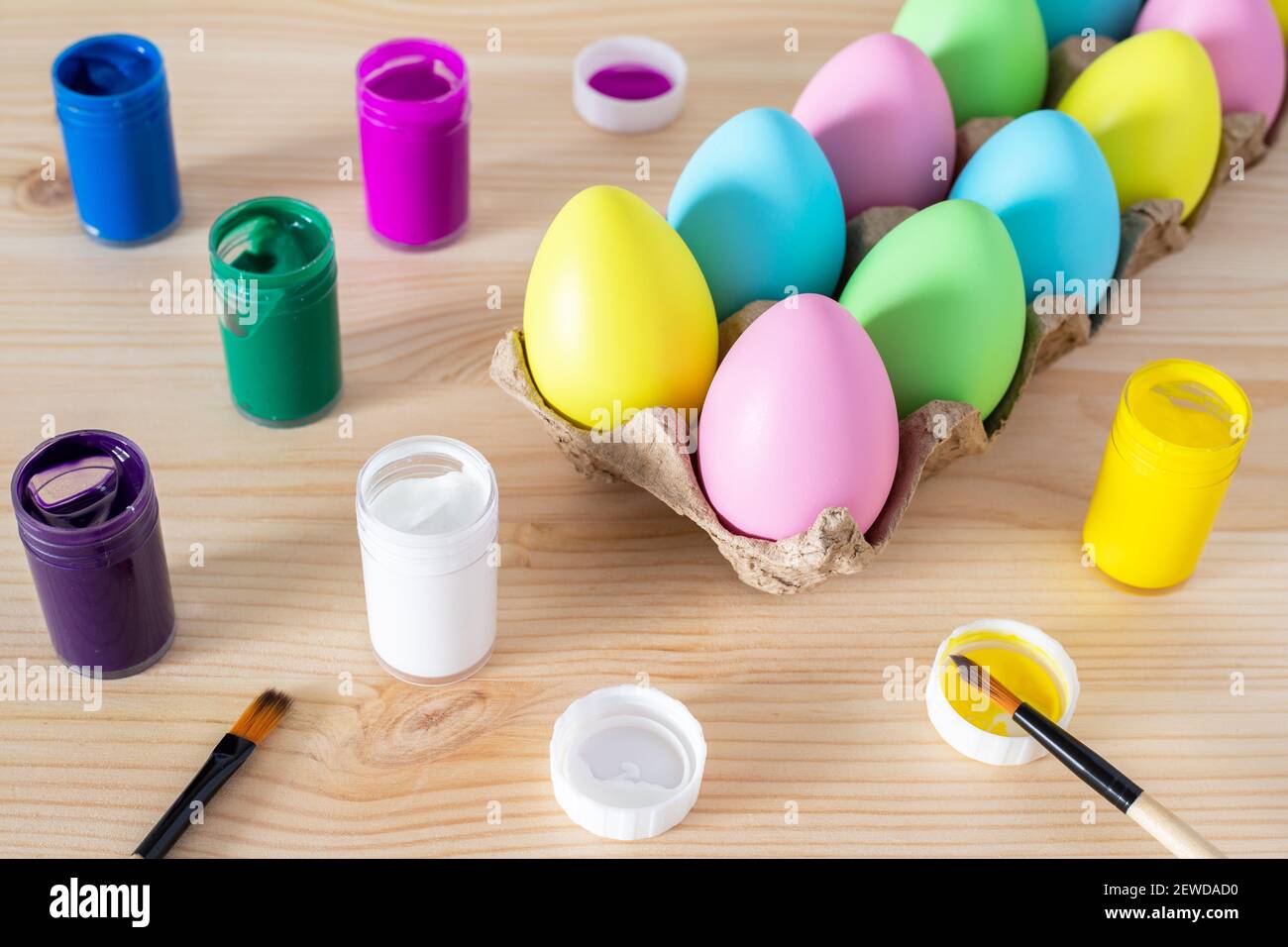Easter eggs and colored paints with paintbrushes on the table. Easter craft concept. Stock Photo
