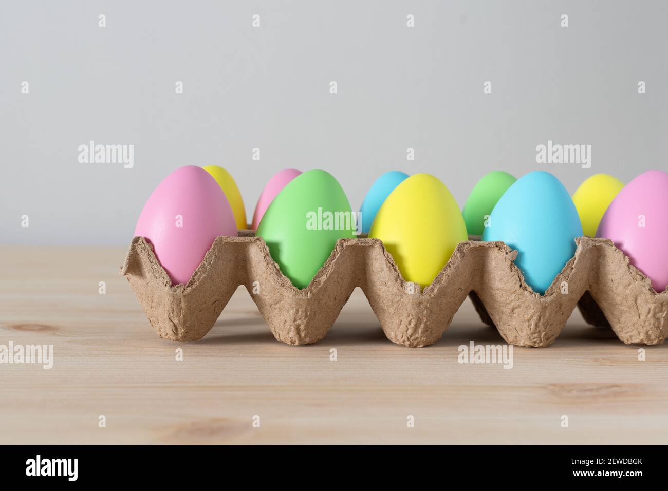 Colorful Easter eggs in egg carton on the table with copy space for text. Stock Photo
