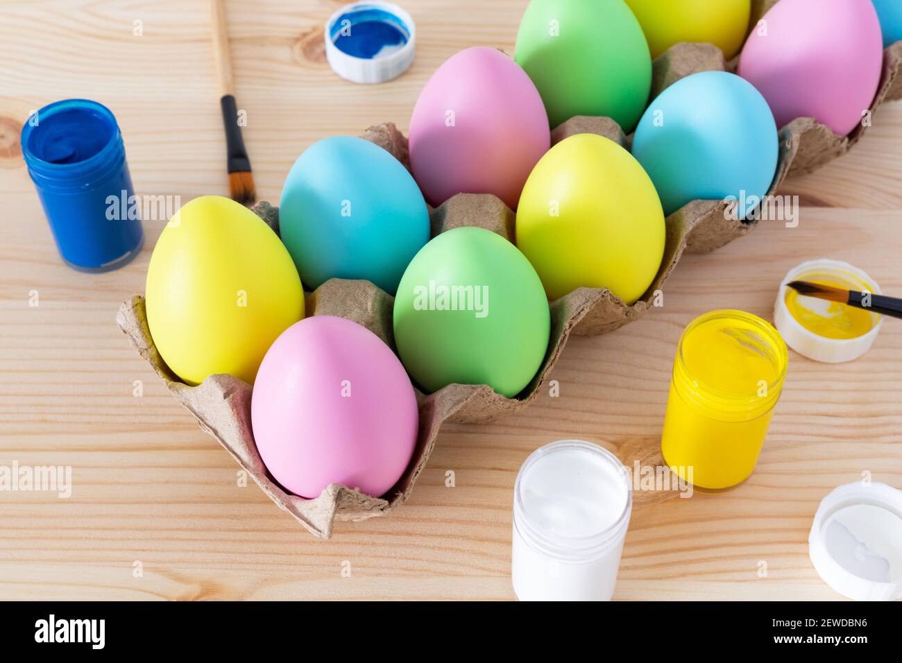 Easter eggs and colored paints with paintbrushes on the table. Easter craft concept. Stock Photo