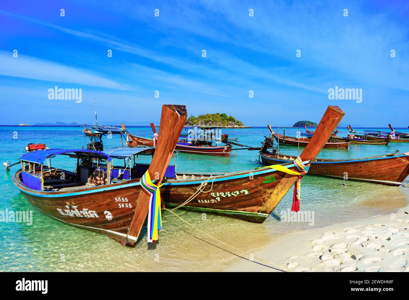 Traditional long tail fishing and tourist boats on Sunrise Beach, Koh Lipe island, Thailand, with blue sky Stock Photo