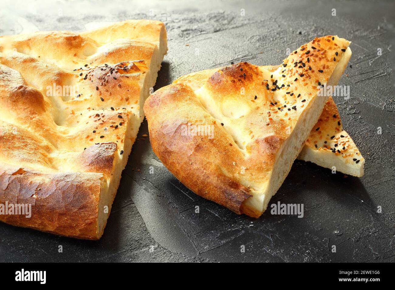 Slices of Ramadan Pita (Ramazan Pidesi) Traditional Turkish bread for holy month Ramadan on black background. Ramadan concept. Stock Photo