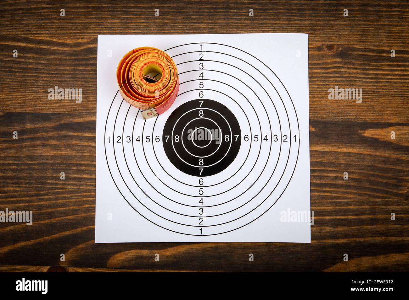 Weight loss and health concept. Tape measure and paper target on a wooden background. Stock Photo