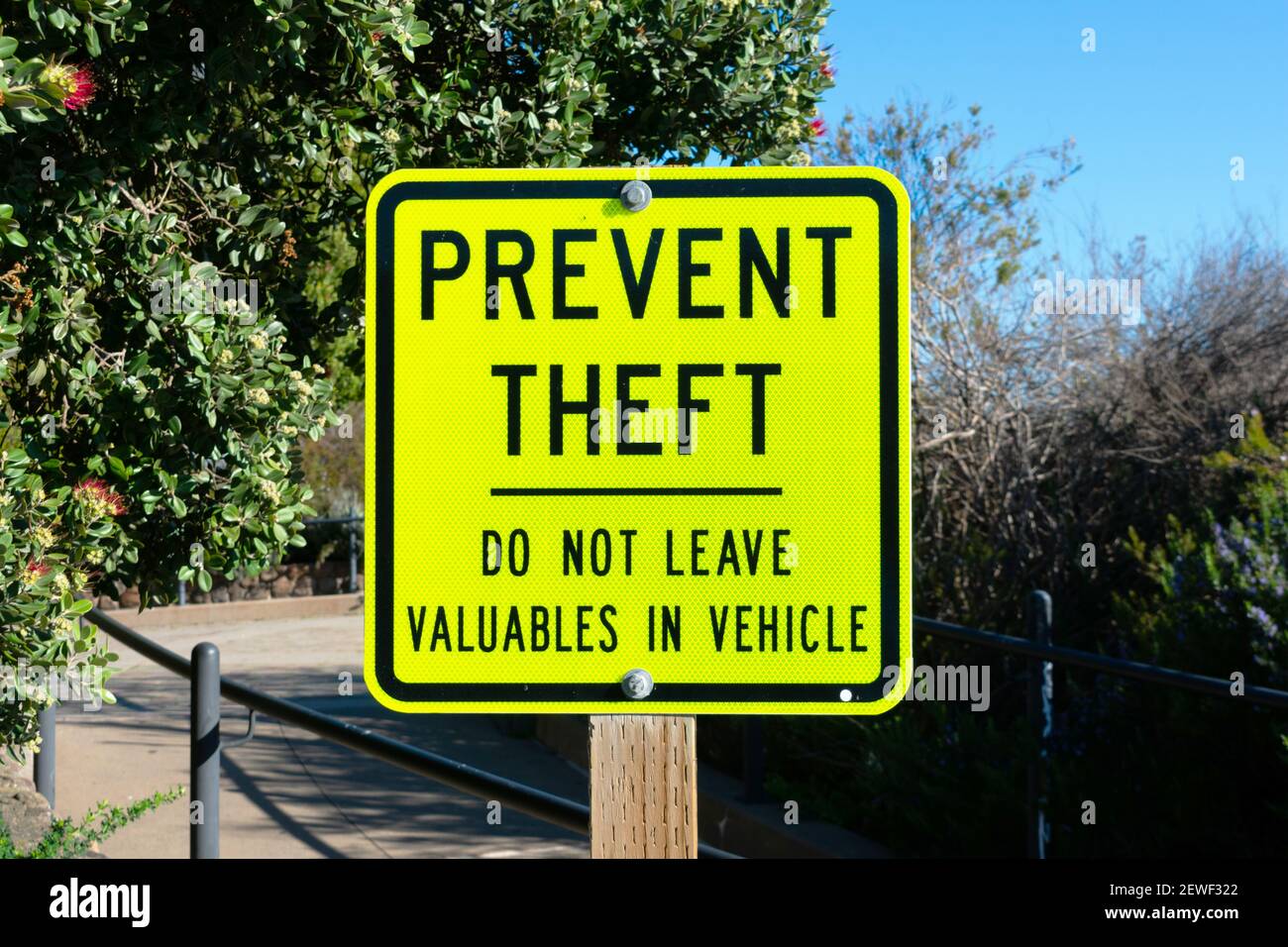Yellow metal prevent theft sign on wooden post. Stock Photo