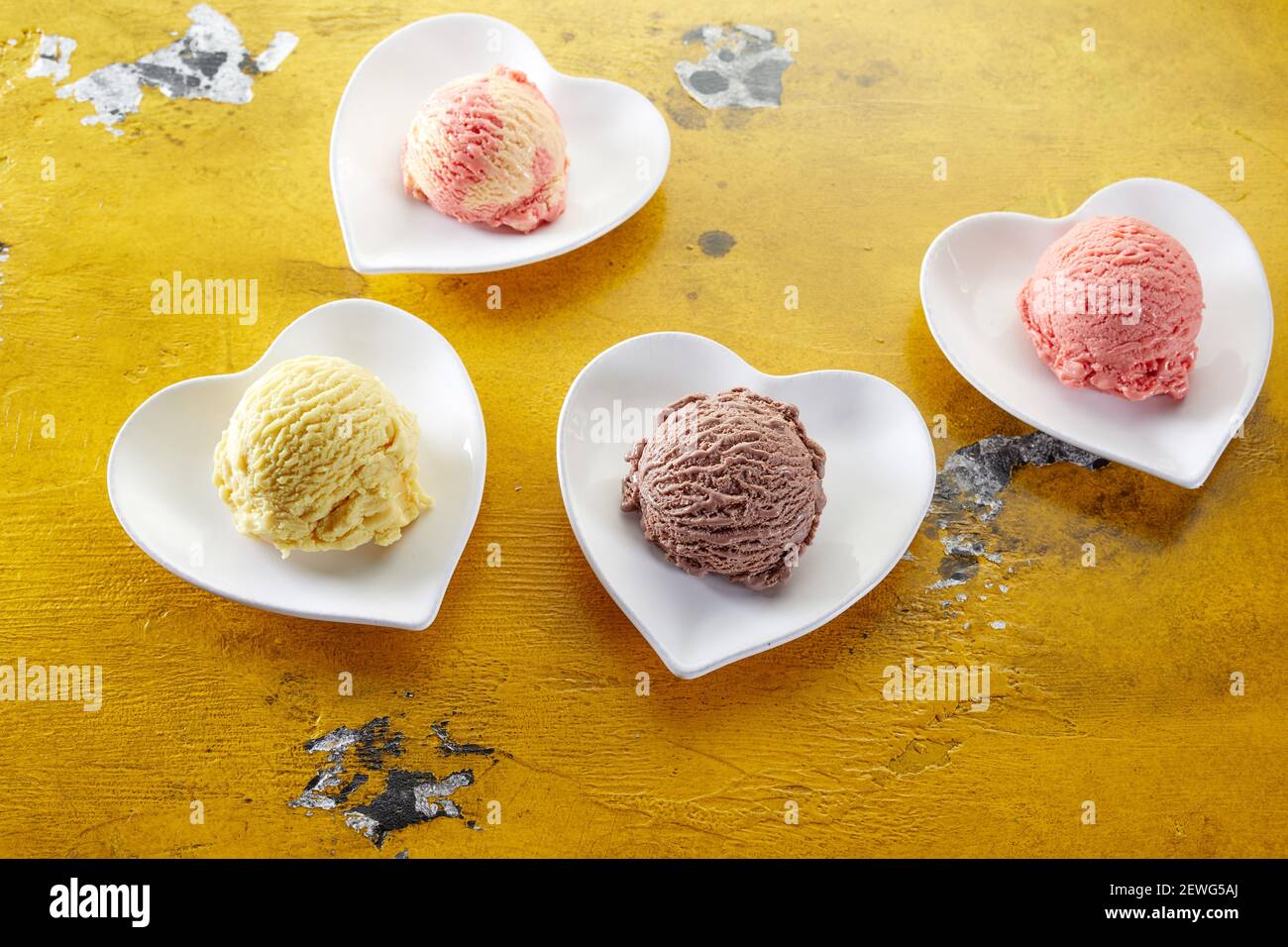 High angle of various ice cream scoops with creamy texture on heart shaped ceramic plates on damaged table Stock Photo