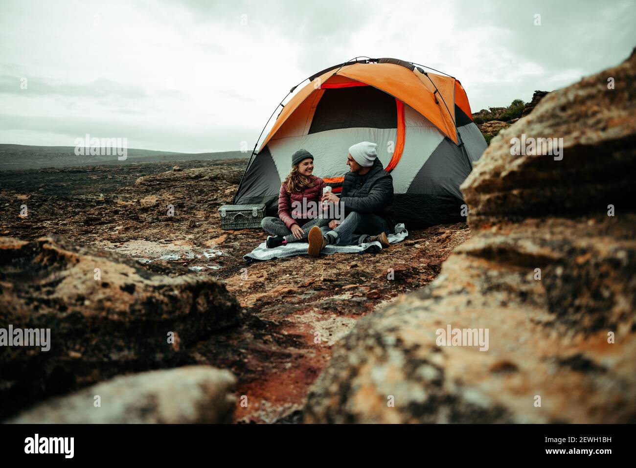 Caucasian romantic couple enjoying camping in mountain sitting under tent Stock Photo