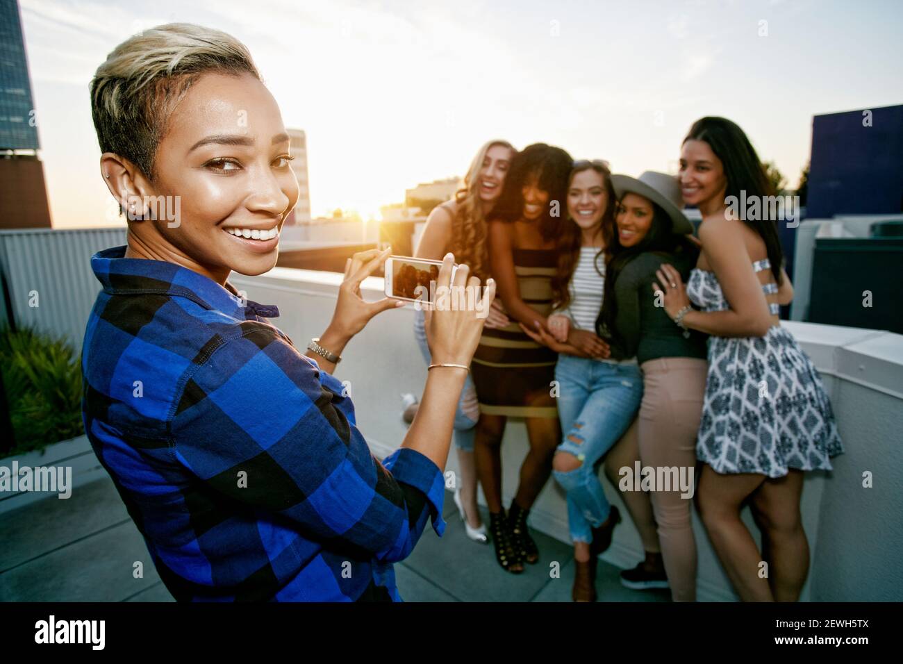 A group of young women partying on a city rooftop at dusk Stock Photo