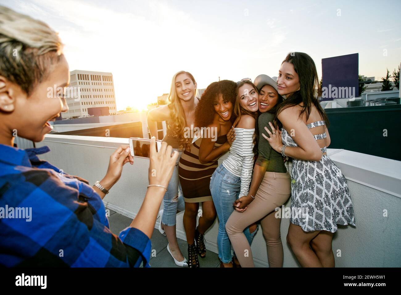 A group of young women partying on a city rooftop at dusk Stock Photo