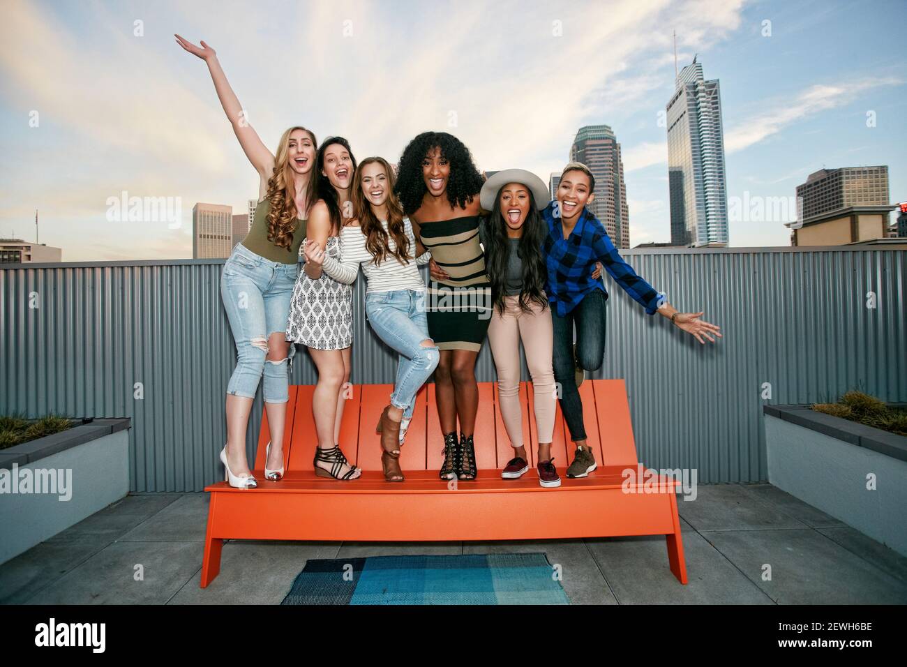 A group of young women partying on a city rooftop at dusk Stock Photo