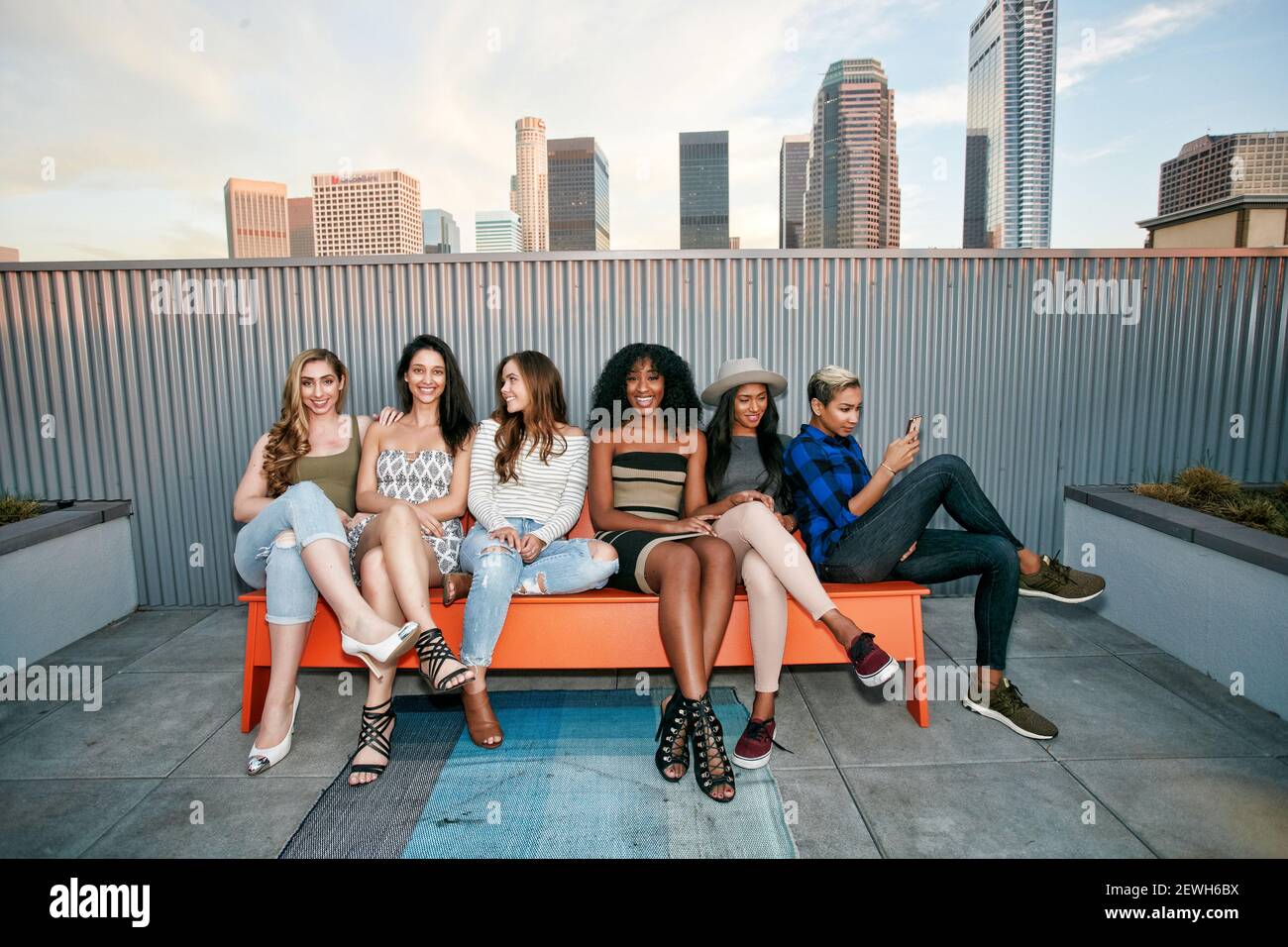 A group of young women partying on a city rooftop at dusk Stock Photo