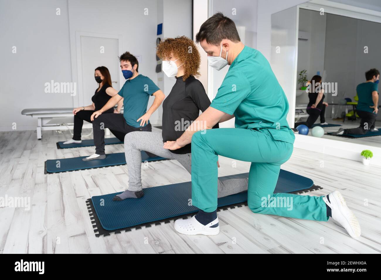 Group of persons on yoga mats assisted by physiotherapist at the rehabilitation clinic. High quality photo. Stock Photo