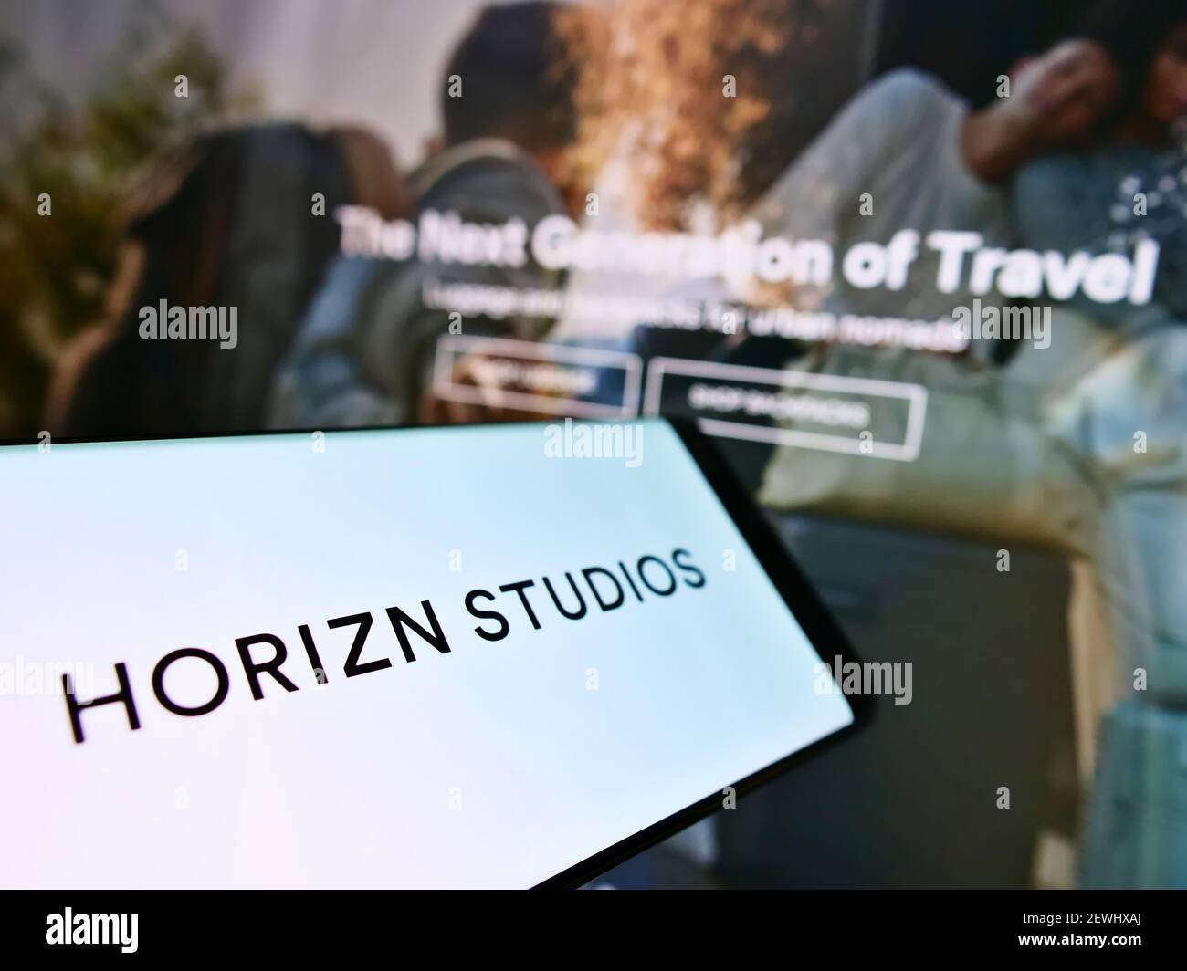 Cellphone with logo of German luggage business Horizn Studios (HS New Travel GmbH) on screen in front of web page. Focus on center of phone display. Stock Photo