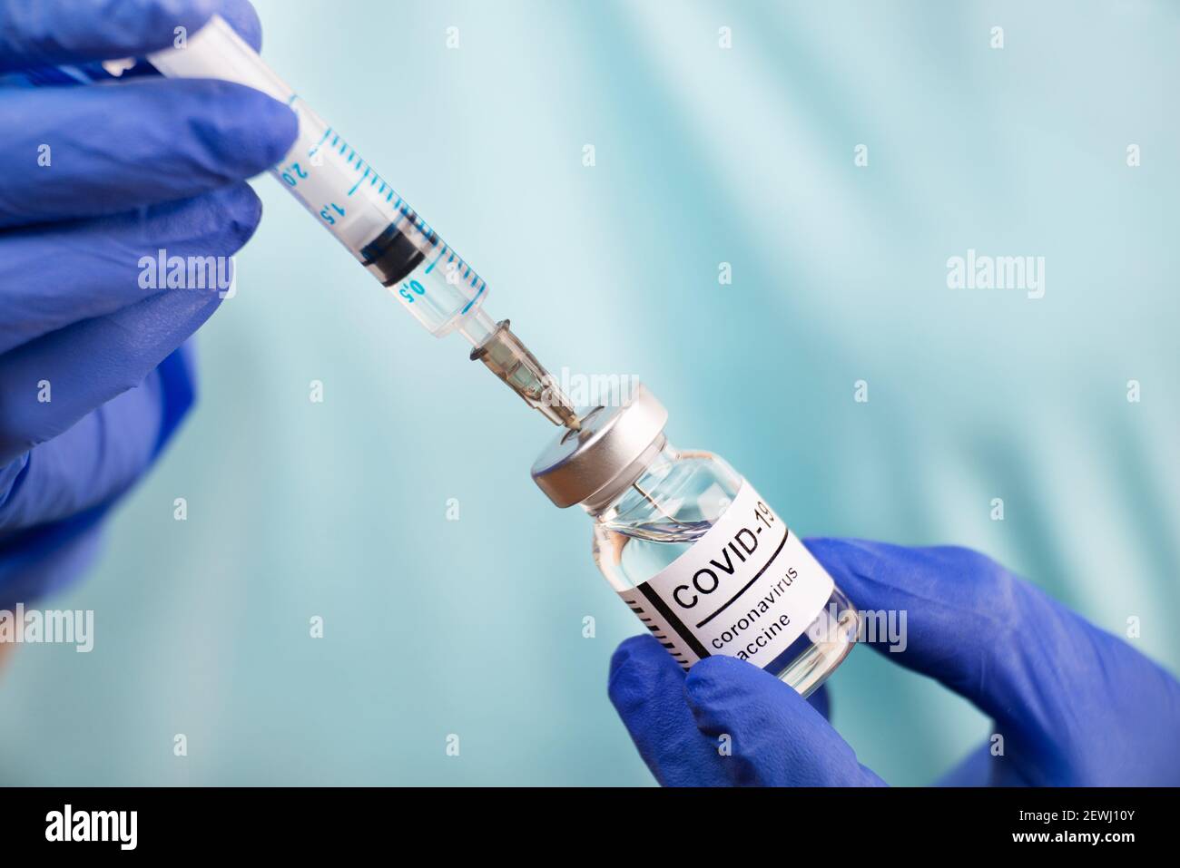 Doctor hands in safety gloves preparing syringe for coronavirus vaccine injection. Stock Photo