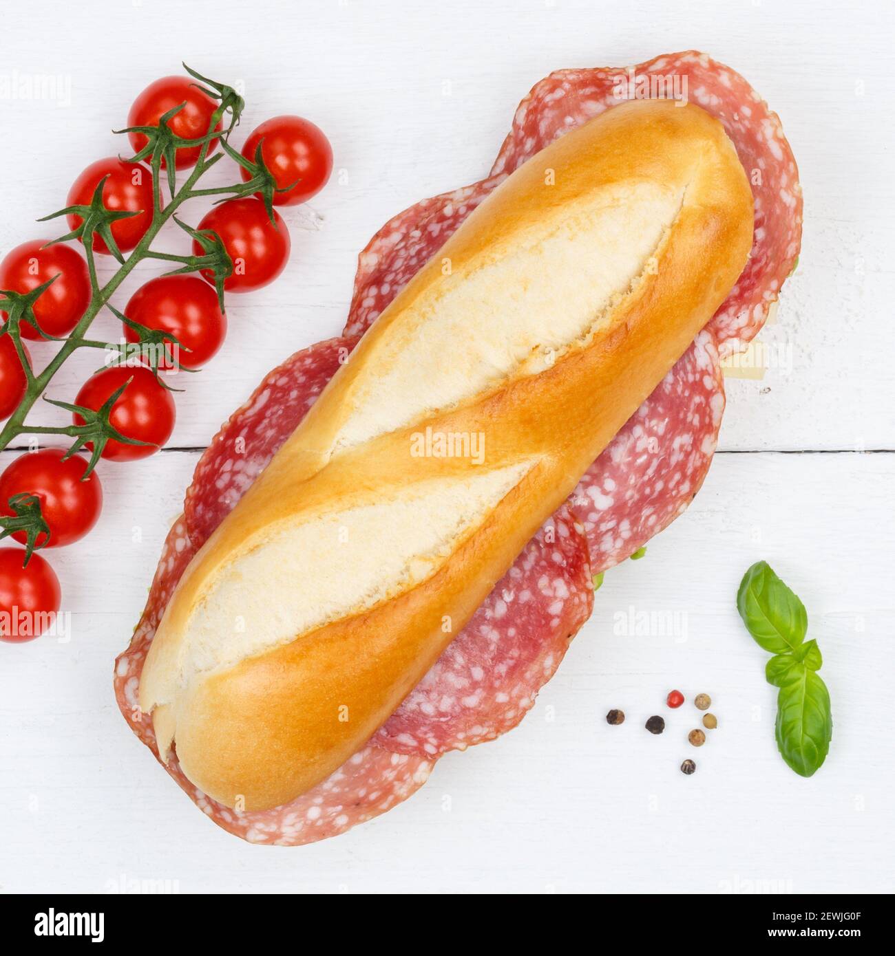 Sub sandwich baguette with salami square from above on wooden board wood. Stock Photo