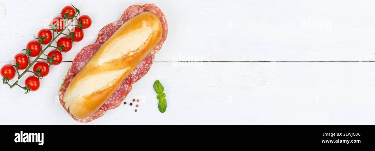 Sub sandwich baguette with salami copyspace copy space banner from above on wooden board wood. Stock Photo