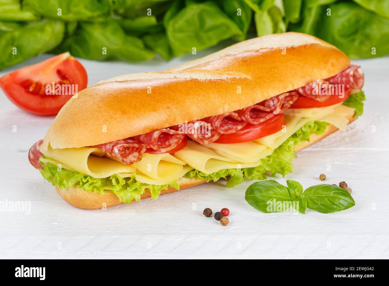 Sub sandwich baguette with salami ham and cheese on wooden board wood. Stock Photo