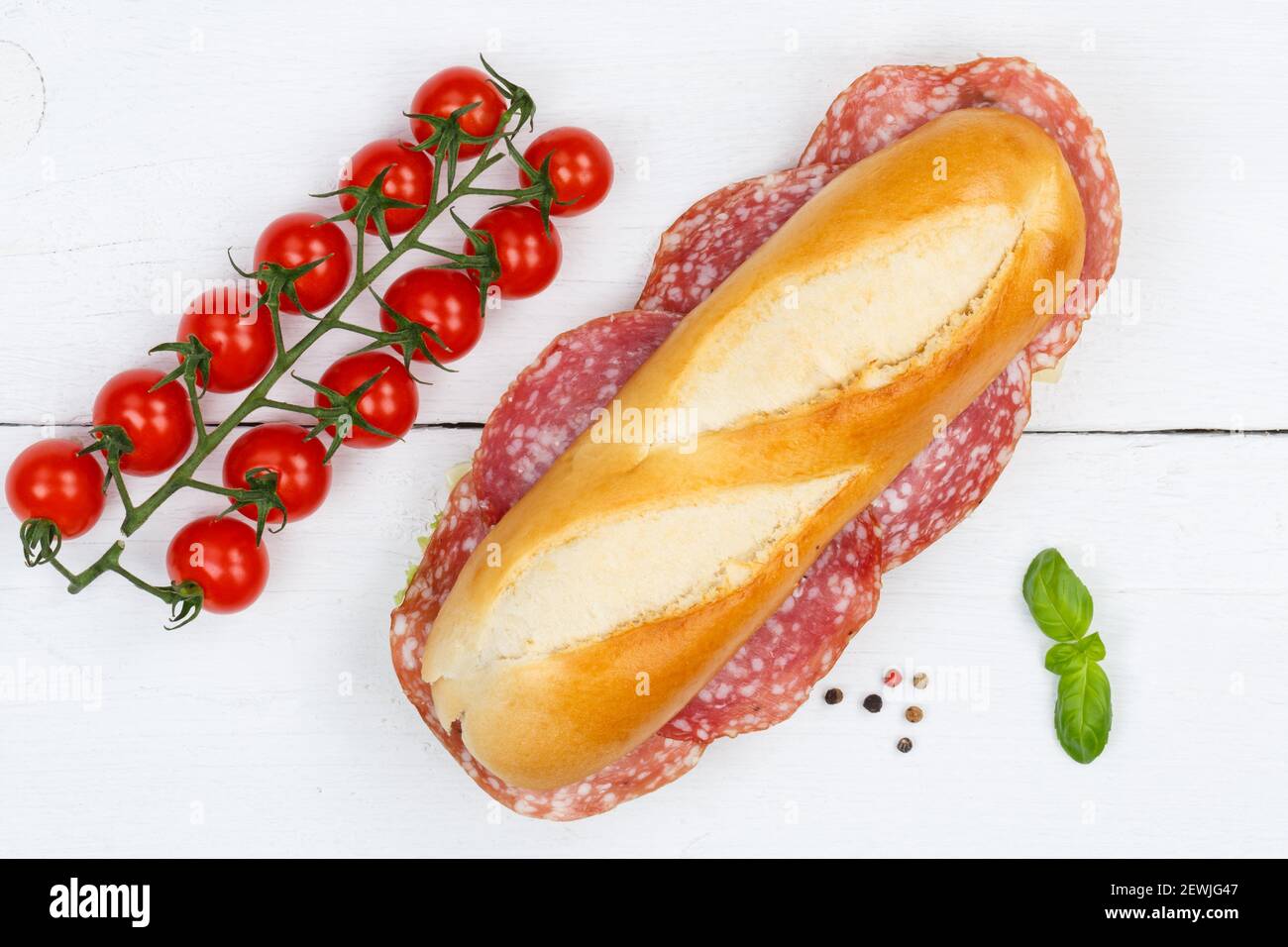 Sub sandwich baguette with salami from above on wooden board wood. Stock Photo