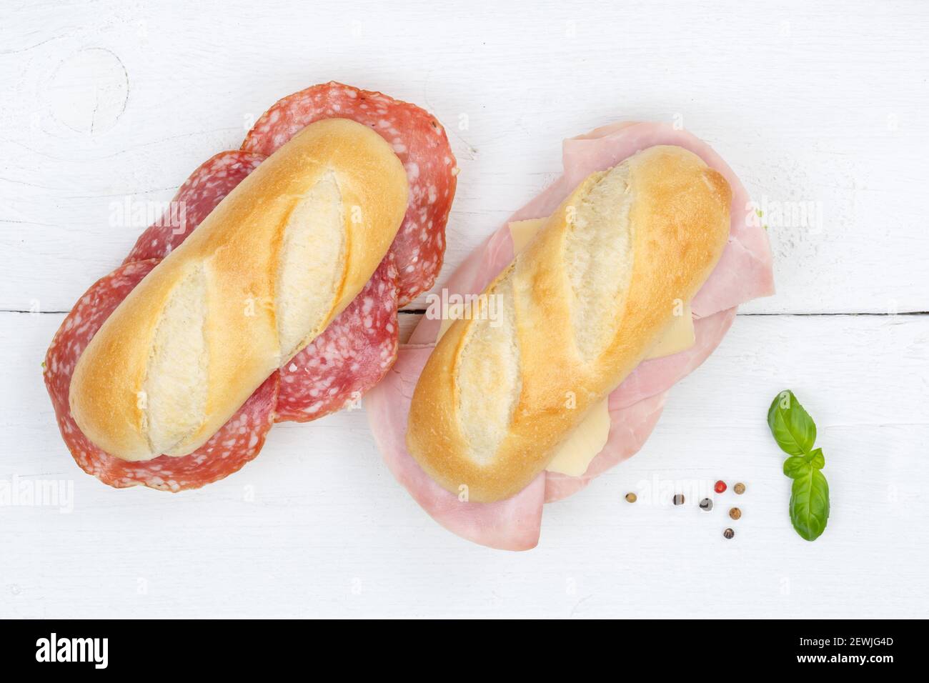 Sub sandwiches baguettes with salami ham and cheese from above on wooden board wood. Stock Photo