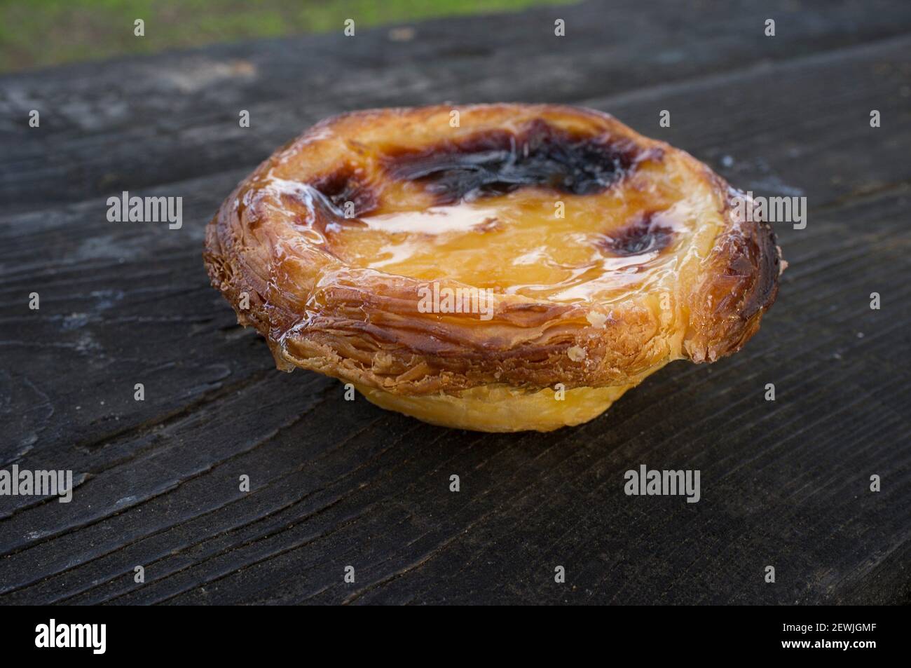 Portuguese egg custard pastry or Pasteis de nata over dark wooden background. Outdoors shot. Stock Photo