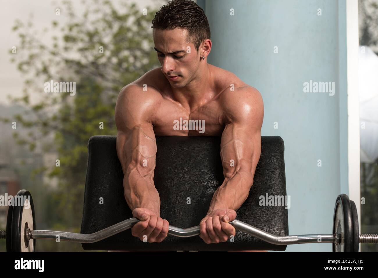 Muscular Man Doing Heavy Weight Exercise For Biceps. Stock Photo