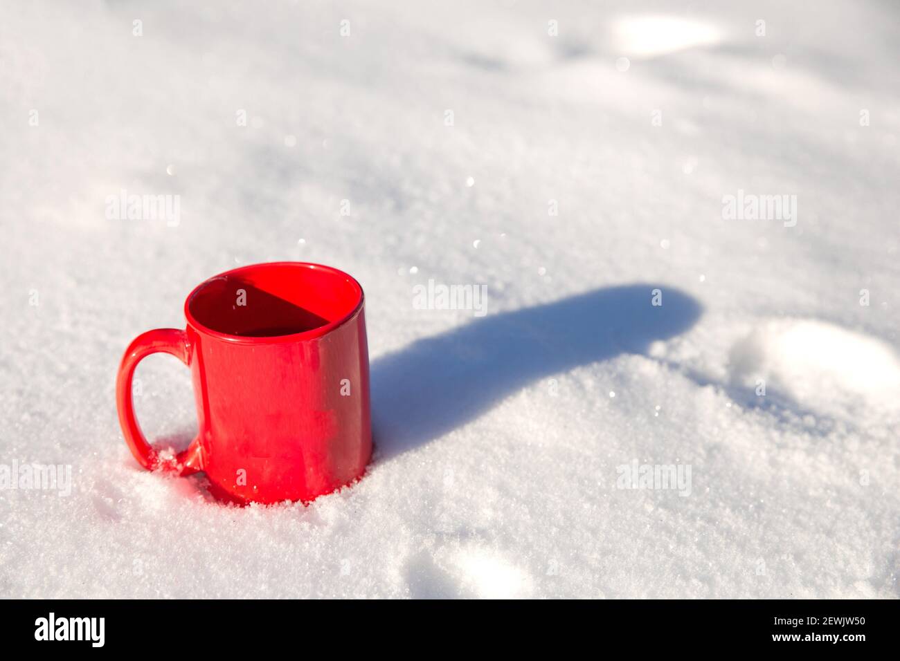 Thermos with a steaming mug of hot drink stands in the snow