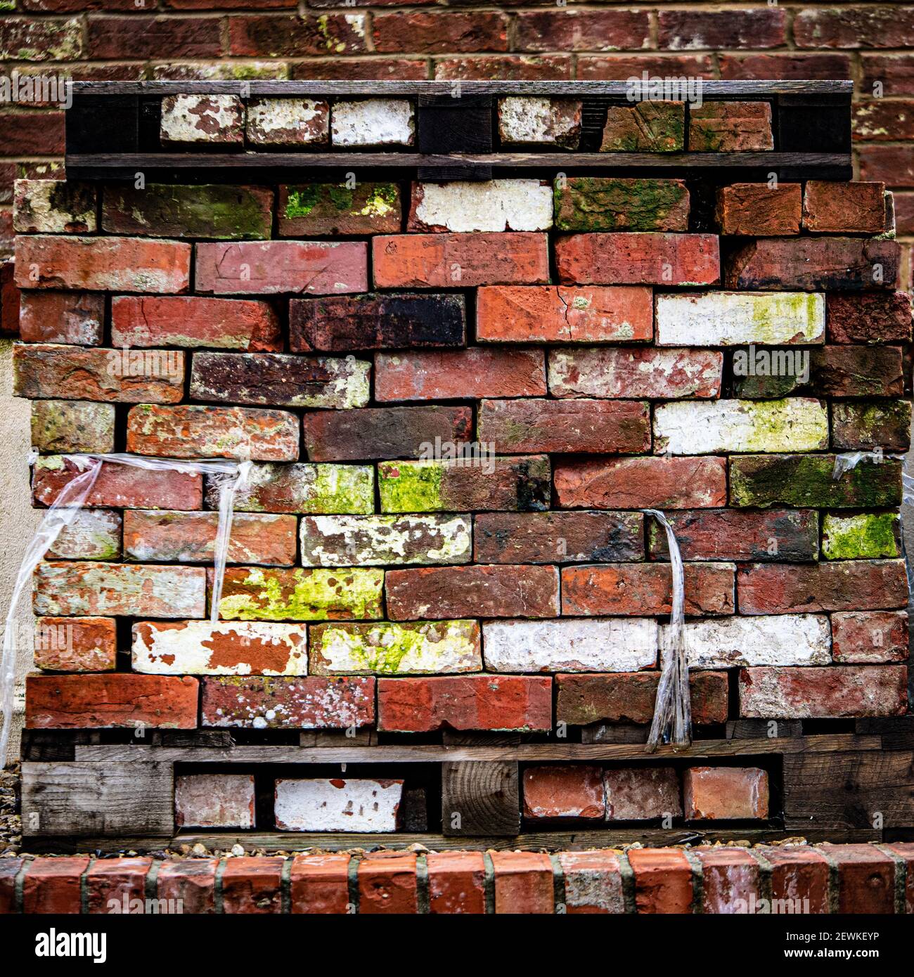 A stack of multi-coloured, aged bricks on pallets in Westbury Leigh, Wiltshire, England, UK. Stock Photo