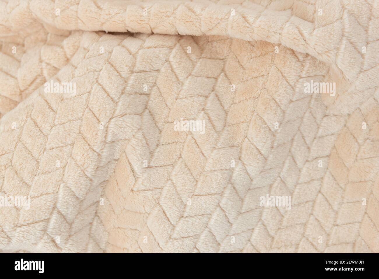 Plush beige blanket with fluffy pile and simple embossed pattern. Stock Photo