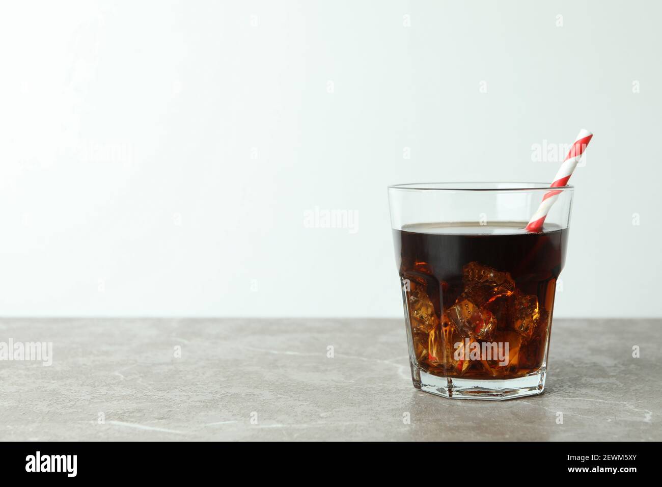 Glass of cola with ice cubes and straw on gray table Stock Photo - Alamy