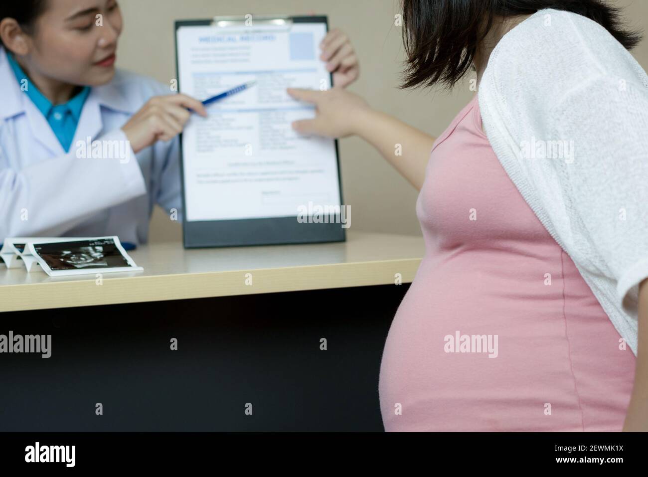 Happy pregnant woman visit gynecologist doctor at hospital or medical clinic for pregnancy consultant. Doctor examine pregnant belly for baby and Stock Photo