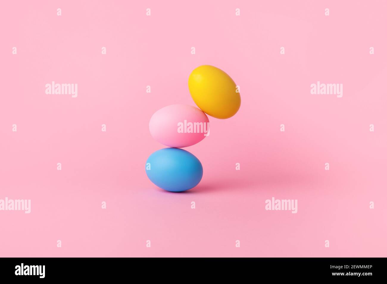 three colorful easter eggs balancing over pink background, balance concept Stock Photo