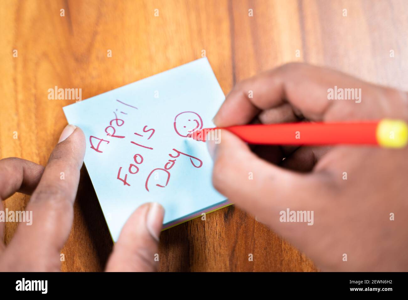 POV shot of hands writing April fools day on sticky notes, concept of preparing for prank or fools day celebration. Stock Photo