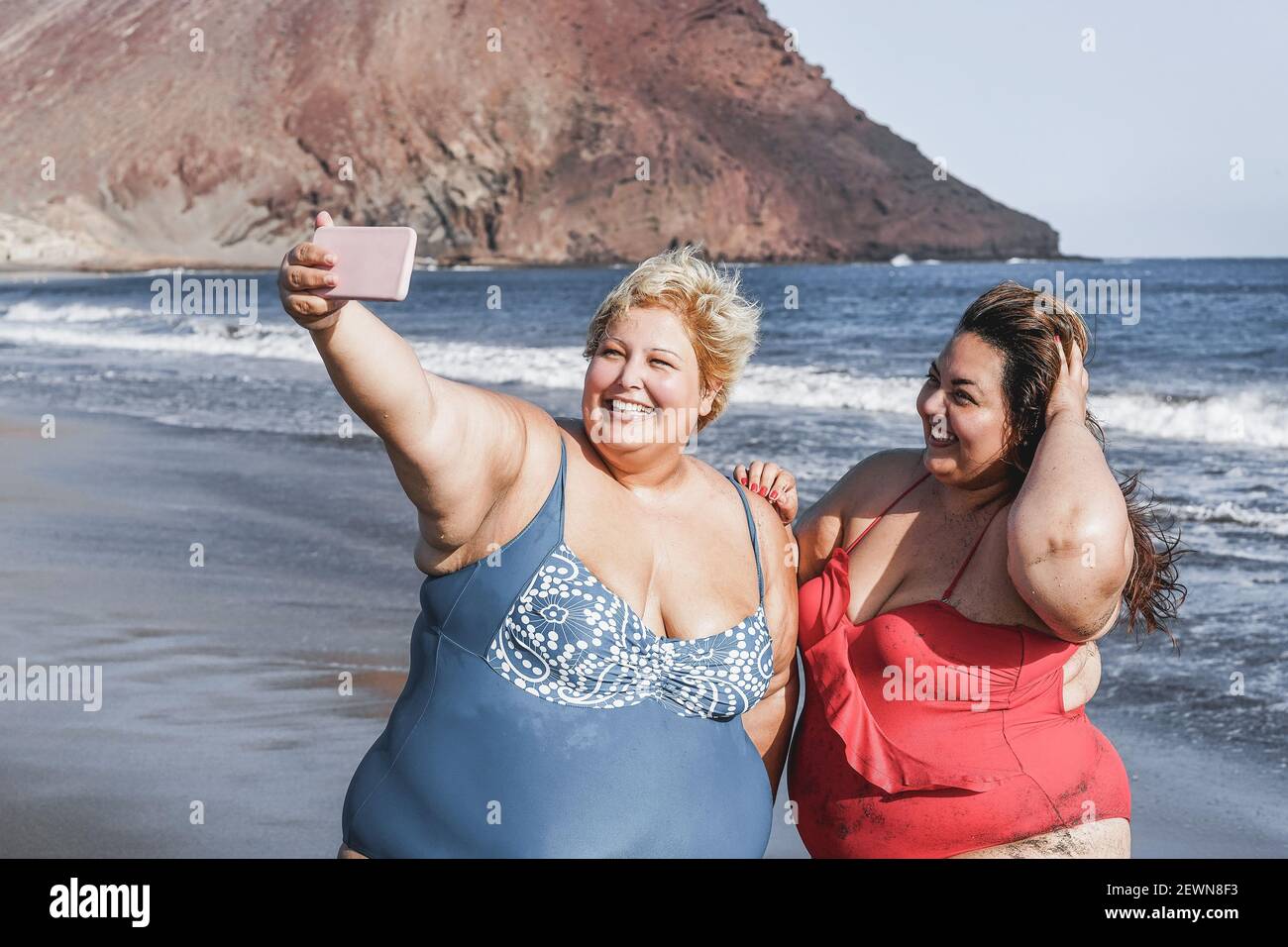 Curvy women friends taking selfie on the beach - Focus on faces Stock Photo
