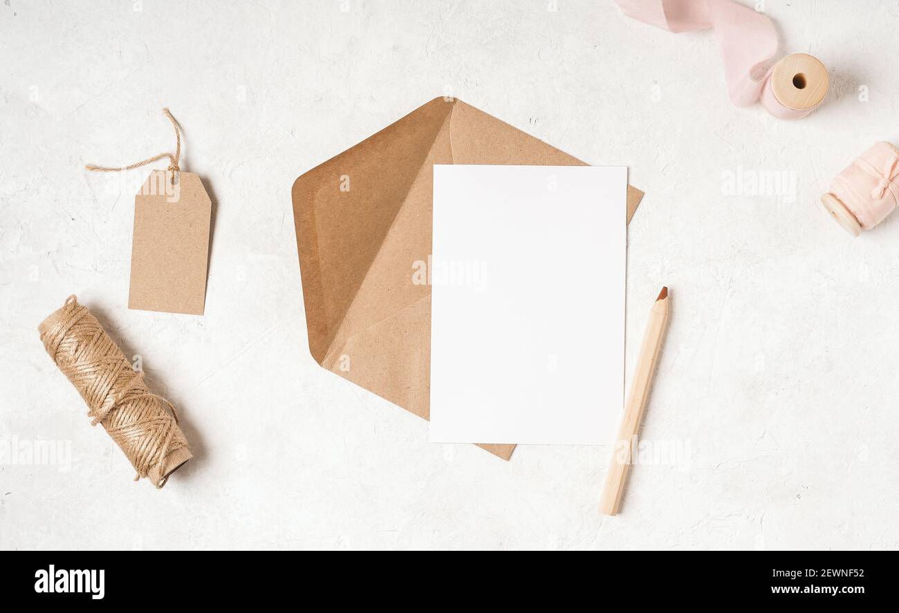 Blank white card with craft paper envelope in hands Stock Photo