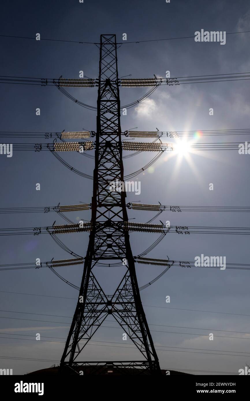 Electricity pylon and cables against a blue sky Stock Photo