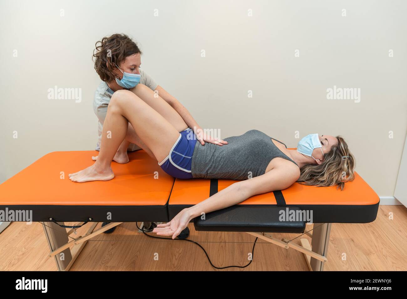 Physiotherapist and patient in Global Postural Re-education session, with pandemic protection mask. Stock Photo