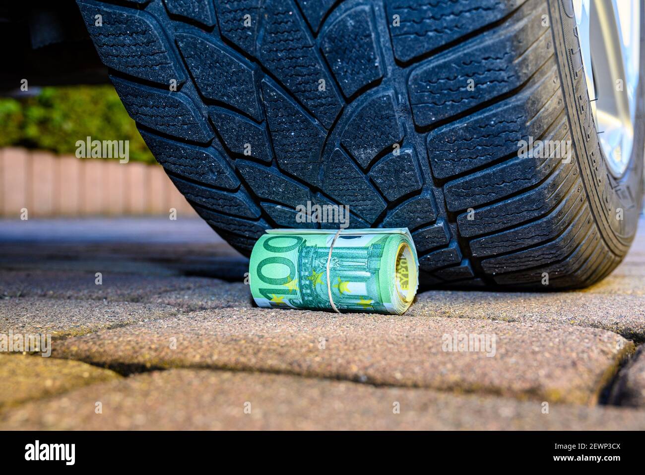 Our money is being hit by inflation and CO2 taxes, and money is being rolled over by wide SUV tires Stock Photo