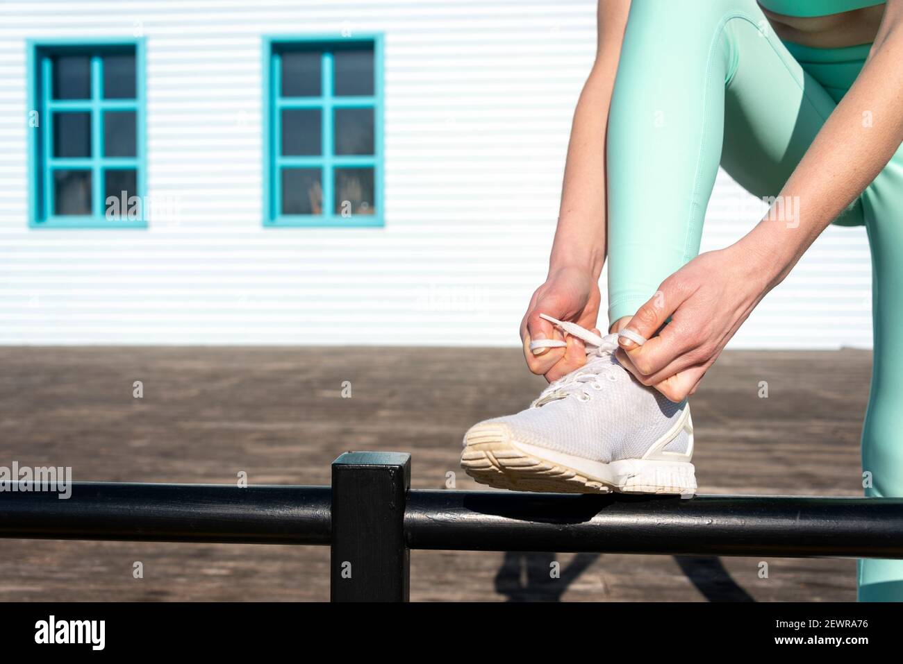 Woman wearing sportswear tying up her trainers, preparing to exercise or run outside. Stock Photo