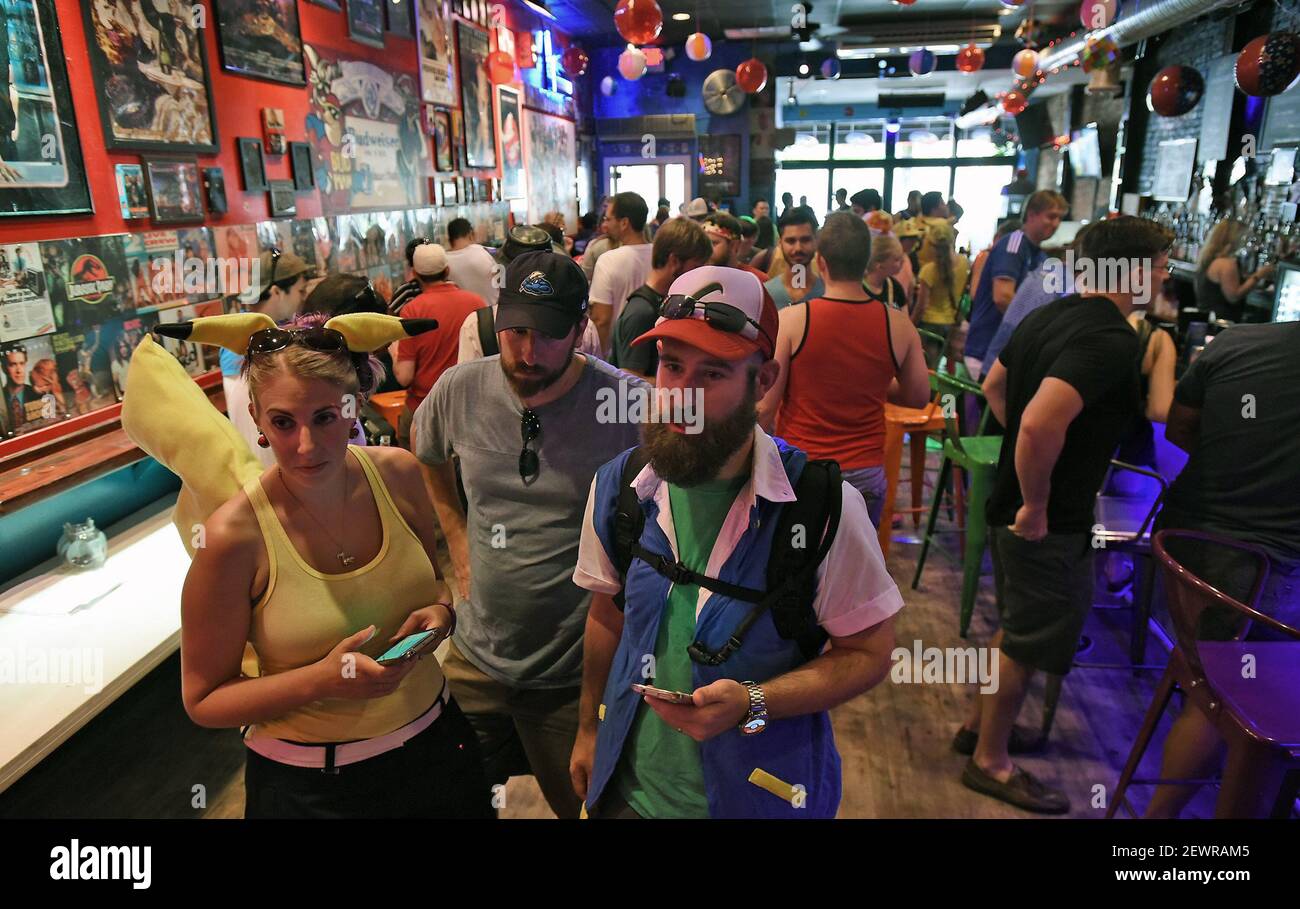 Jessica, left, and Dan Caswell, right, check in with Wayne Judd, not pictured, for the Pokemon Go Bar Crawl at Coglin's Raleigh bar during the Pokemon Go event on July 24, 2016 in downtown Raleigh, N.C. (Photo by Chuck Liddy/Raleigh News & Observer/TNS) *** Please Use Credit from Credit Field *** Stock Photo