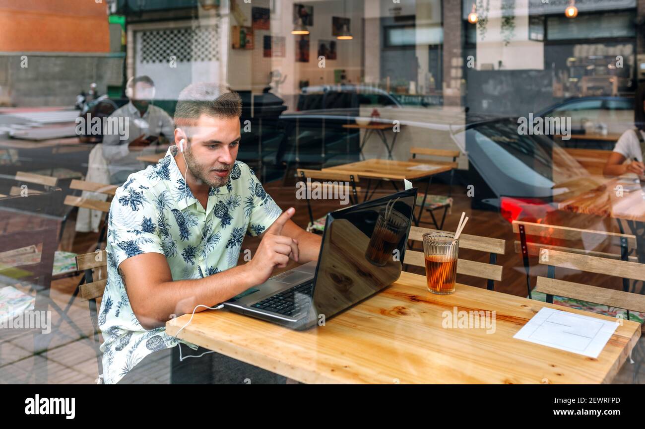 Man with earphones working with laptop from coffee shop Stock Photo
