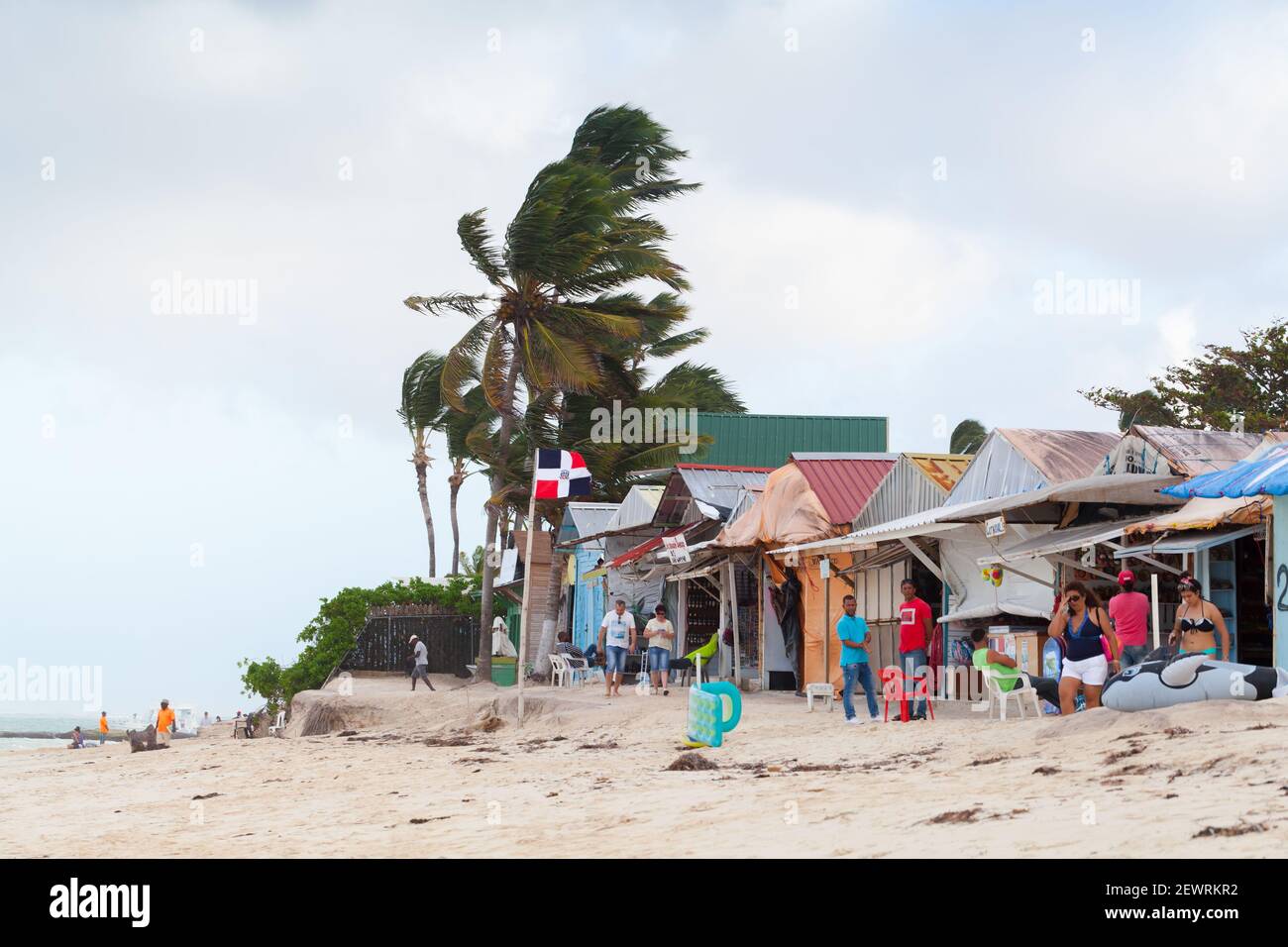 Punta Cana, Dominican republic - January 14, 2020: Tourists walk on a sandy beach of Punta Cana resort near small souvenir shops and beach restaurants Stock Photo