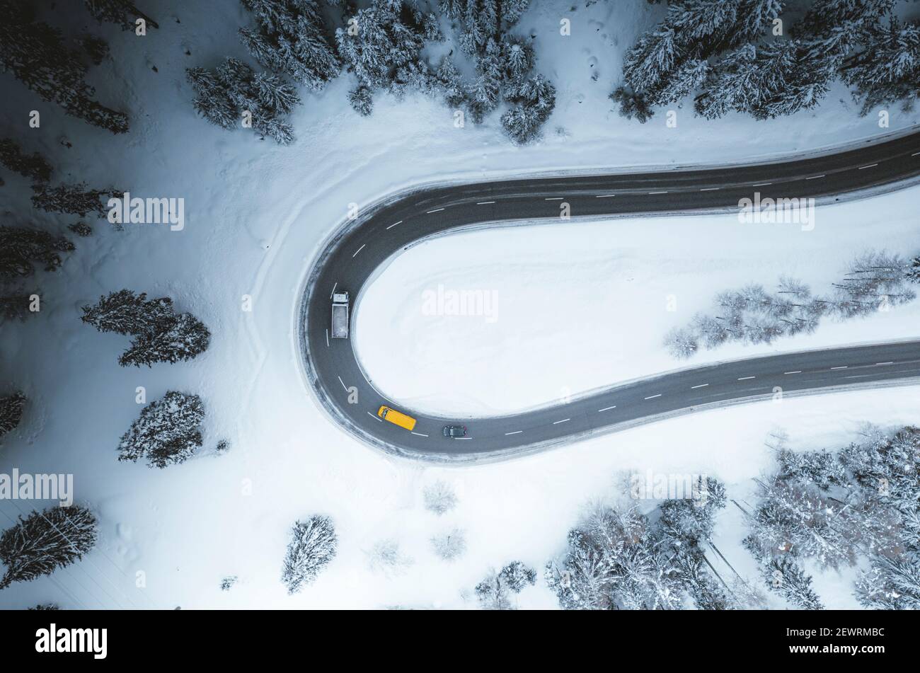 Aerial view of cars driving on bends of snowy mountain road in winter ...