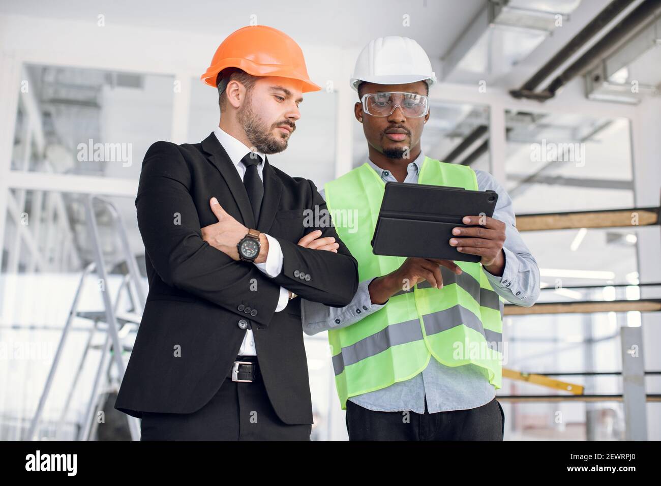 Multiethnic men using tablet for work on construction project Stock Photo