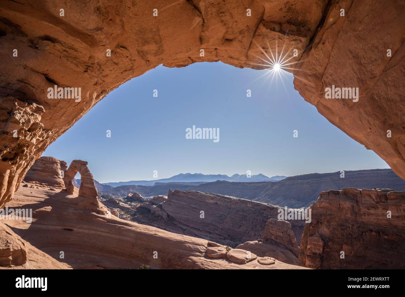 View of Delicate Arch through Frame Arch with sunburst, Arches National Park, Utah, United States of America, North America Stock Photo