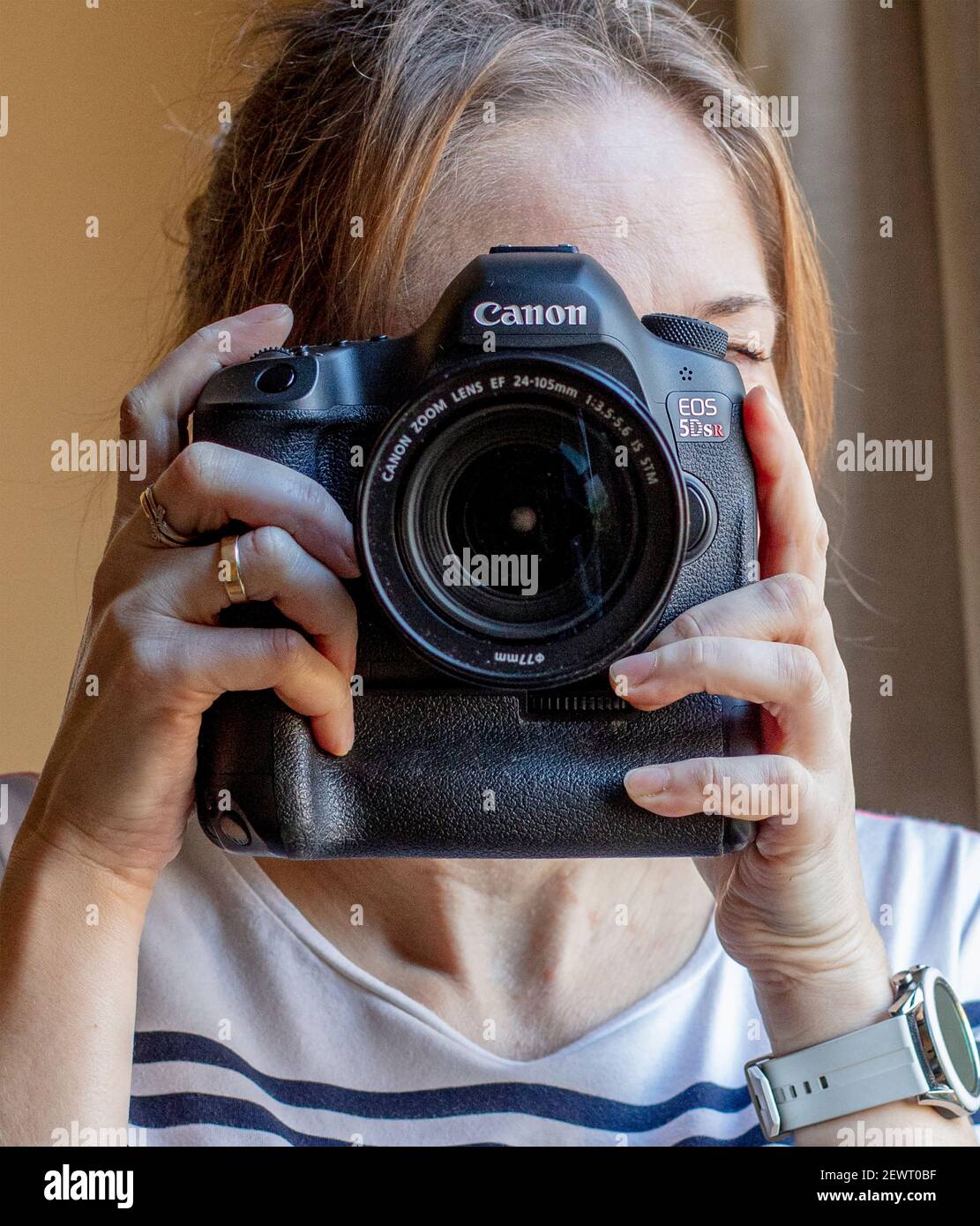 Young woman using a Canon EOS 5DSR with external battery pack, pointing  directly at camera Stock Photo - Alamy