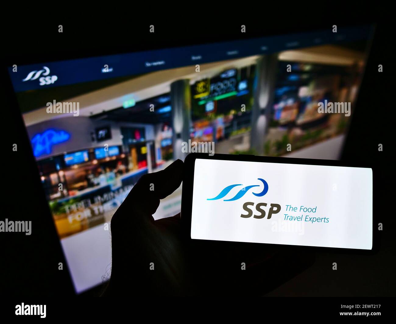 Person holding smartphone with logo of British foodservice company SSP Group plc on screen in front of website. Focus on phone display. Stock Photo