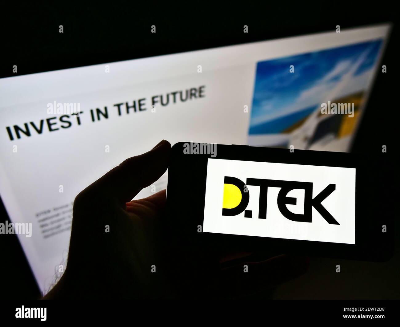 Person holding smartphone with logo of Ukrainian energy company DTEK on screen in front of website. Focus on phone display. Unmodified photo. Stock Photo