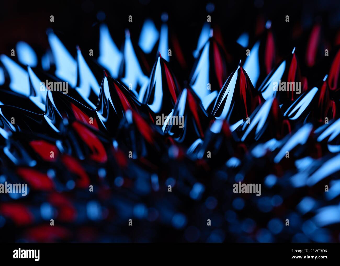 A close up macro image of ferrofluid reacting to a magnetic force, showing the spikes that form lit with blue and red lighting. Stock Photo