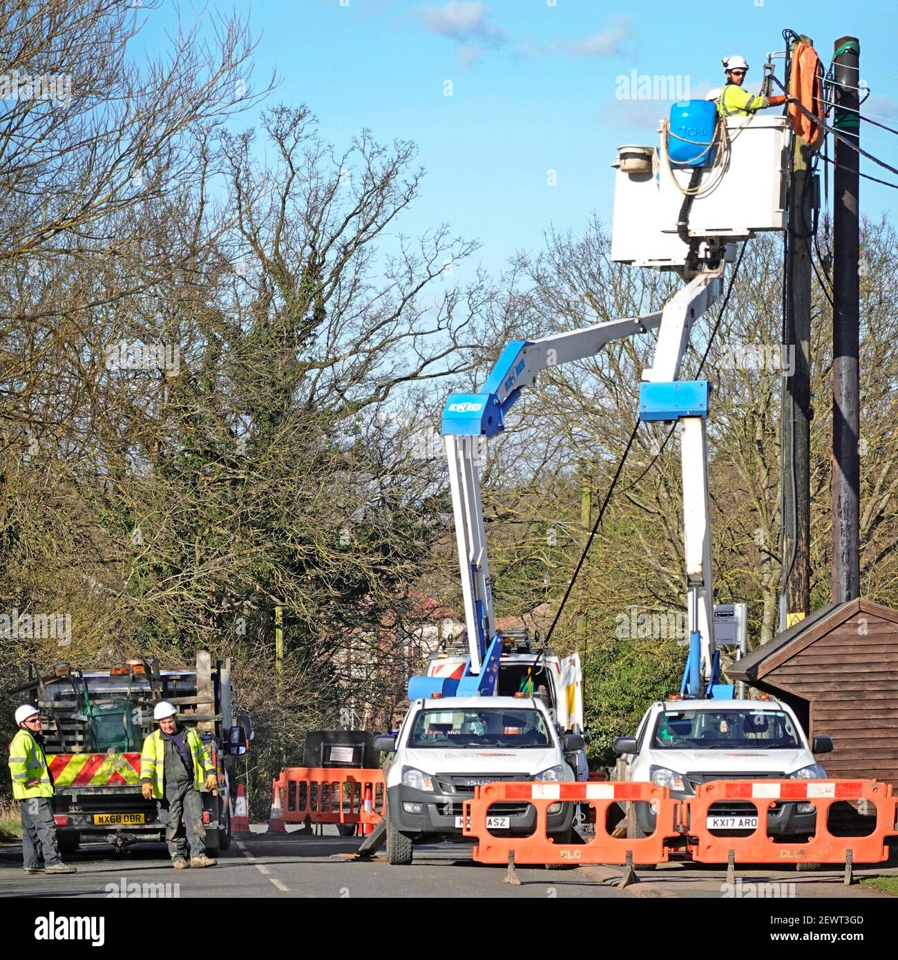 UK Power Networks distribution business cherry picker truck & electrician workers connecting new electricity supply cable at top of pole Essex UK Stock Photo